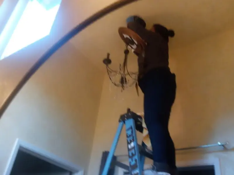 Electrician installing a chandelier in a Grand Mound residence